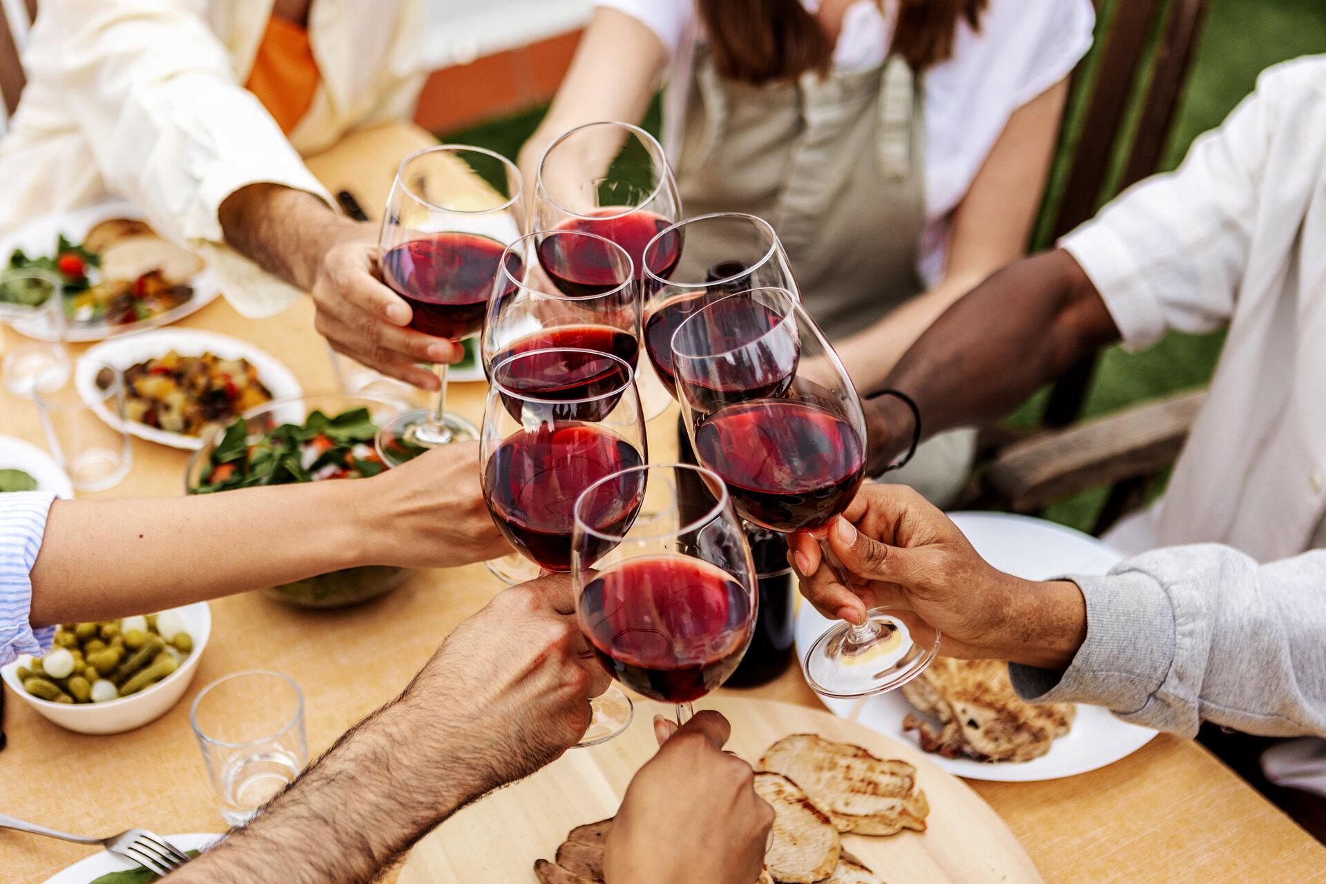 Eine Gruppe junger Leute stößt auf einer Dachterrassenparty mit Rotwein an