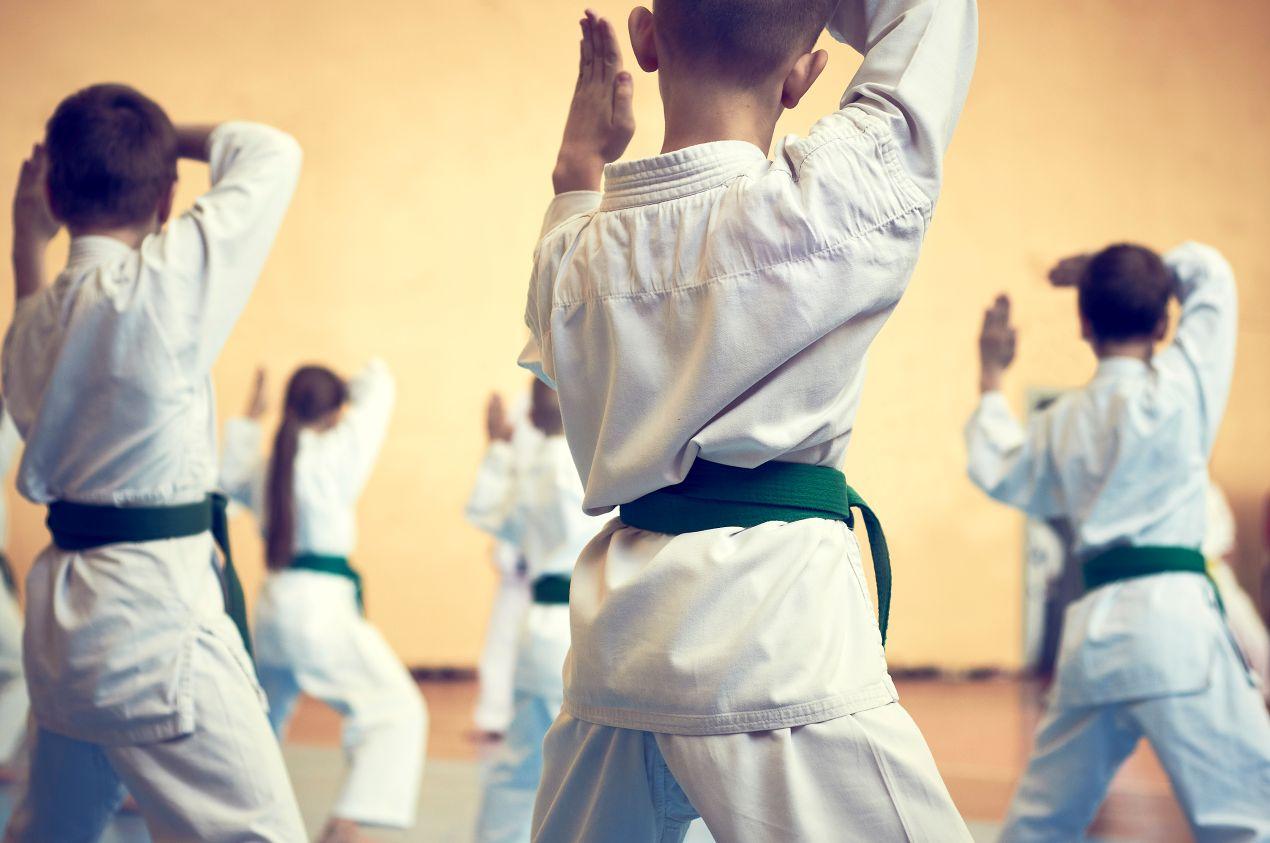 Gruppe von Kindern mit gruenem Guertel beim Karate-Training in Muenchen, Fokus auf koerperlicher Disziplin und Bewegung