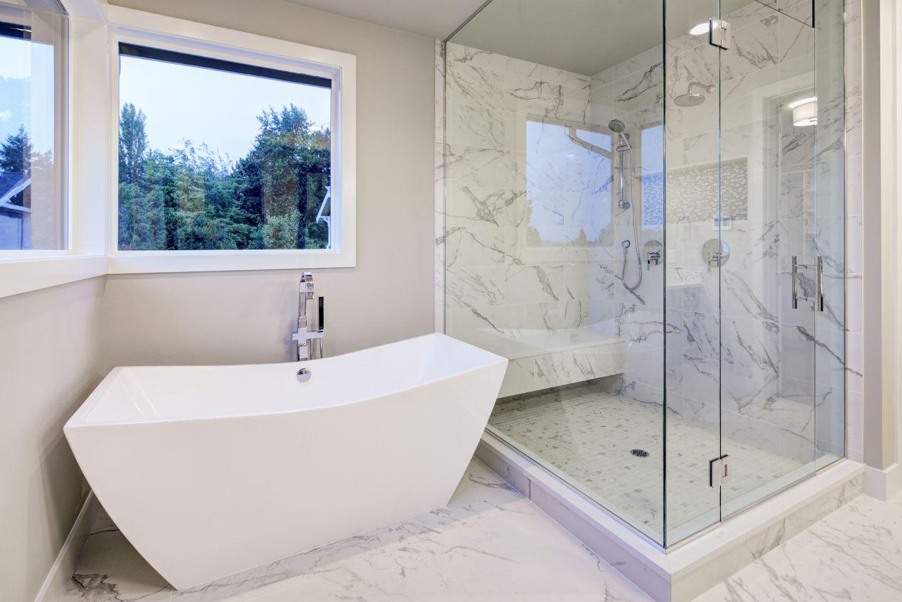 Modernes Badezimmer mit Glasdusche und nahtloser Duschrückwand in heller Marmoroptik