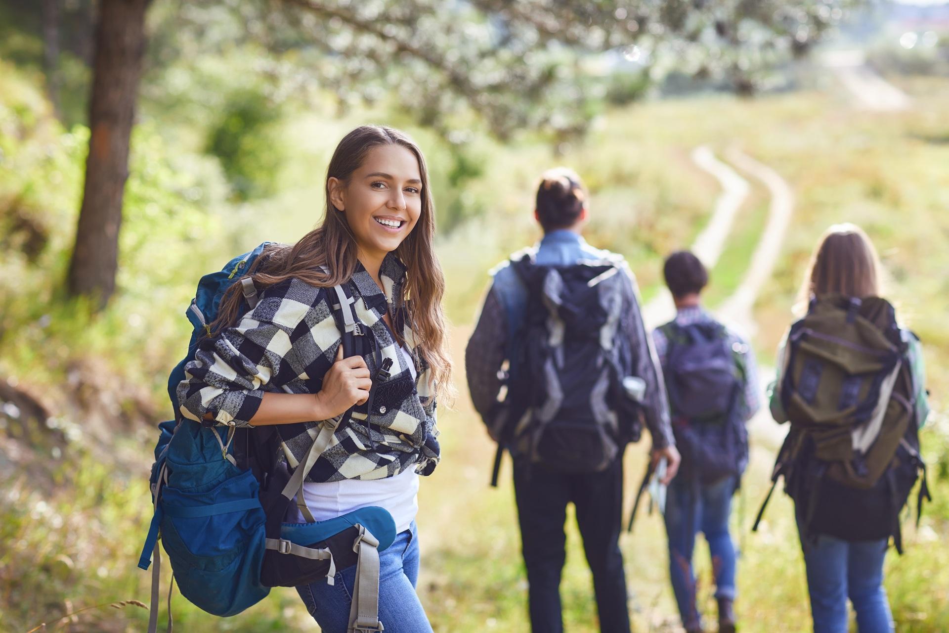 Frau mit Rucksack lächelt bei Wanderung | Base Liquid