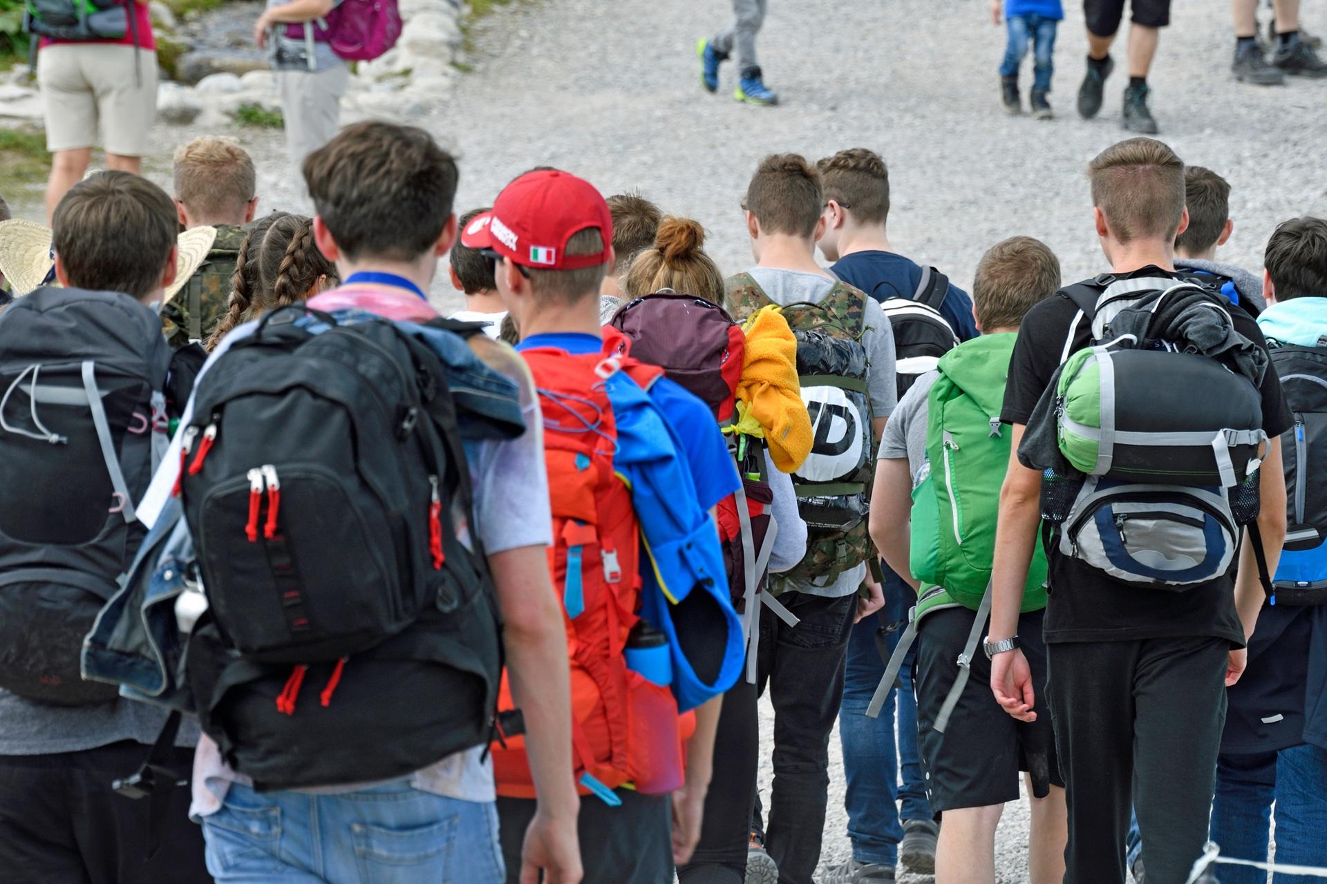 Jugendliche laufen mit großen Rucksäcken in Reihe | Klassenfahrt Berlin