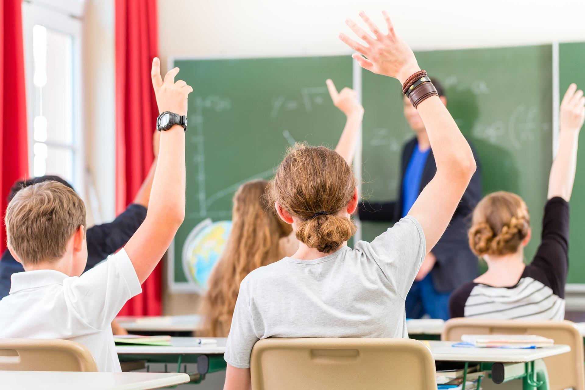 Schueler heben im Klassenzimmer die Hand | Klassenfahrt Berlin