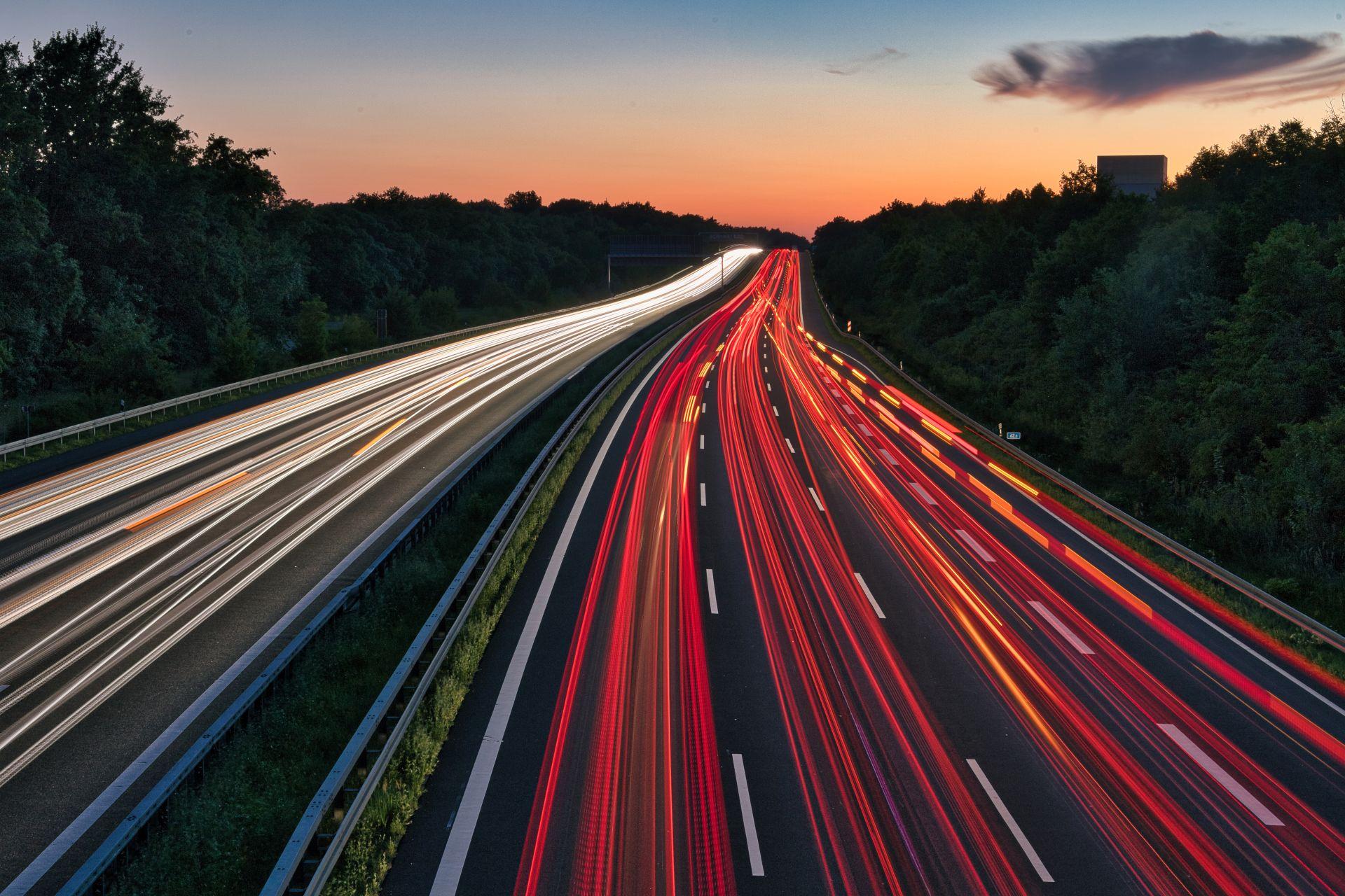 Lichtspuren von Autos auf einer Autobahn bei Sonnenuntergang