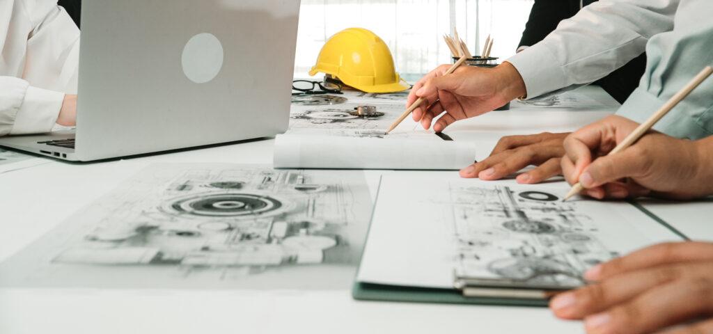 Ingenieure arbeiten an technischen Zeichnungen und planen den Einsatz von Betonschrauben fuer praezise Bauverbindungen